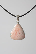 Treasured Energies scolecite teardrop crystal pendant on black cord against a dark background
