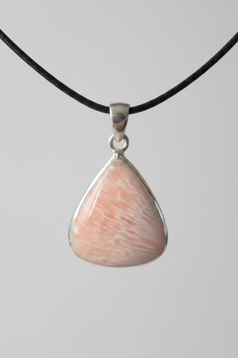 Treasured Energies scolecite teardrop crystal pendant on black cord against a dark background