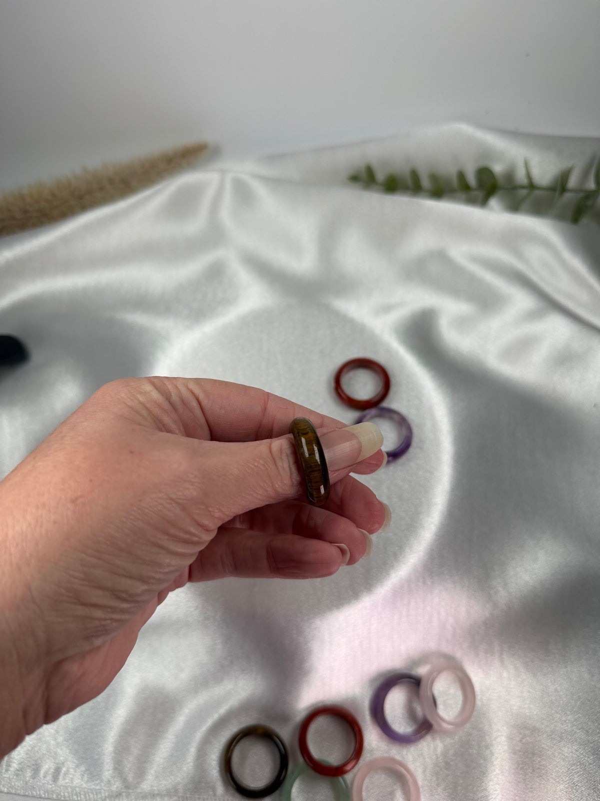 Treasured Energies crystal sphere holders spread across fingers on a white fabric background