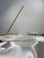 Natural selenite incense holder with a single incense stick on white fabric