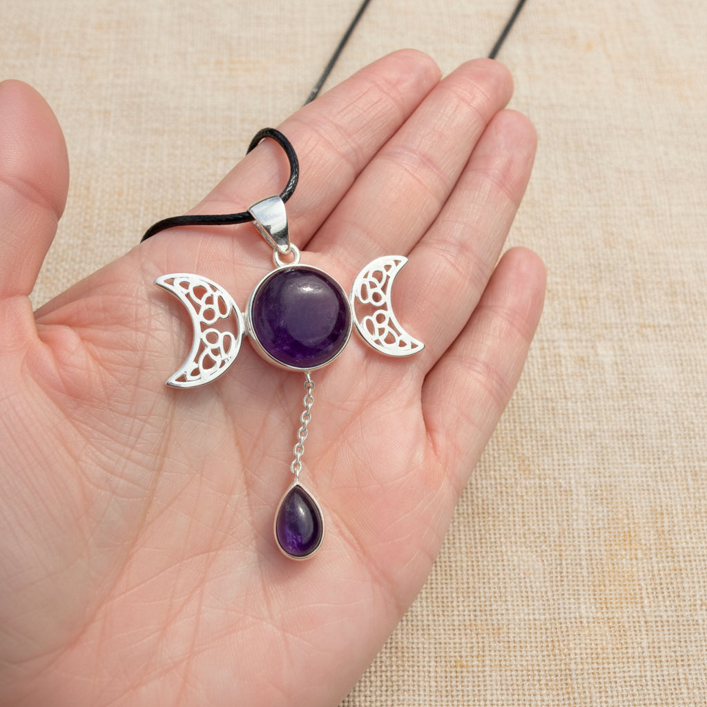 Triple moon amethyst necklace with a dangling teardrop amethyst pendant held against green grass