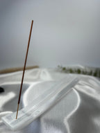 Natural selenite incense holder with a single incense stick in soft natural light