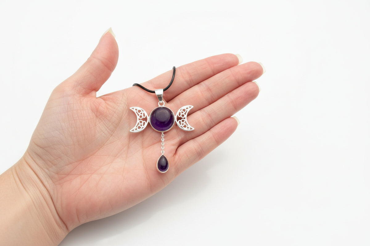 Triple moon amethyst pendant necklace held in a hand, showing the purple stone and pendant design