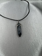Snowflake obsidian necklace crystal point pendant photographed against a light background