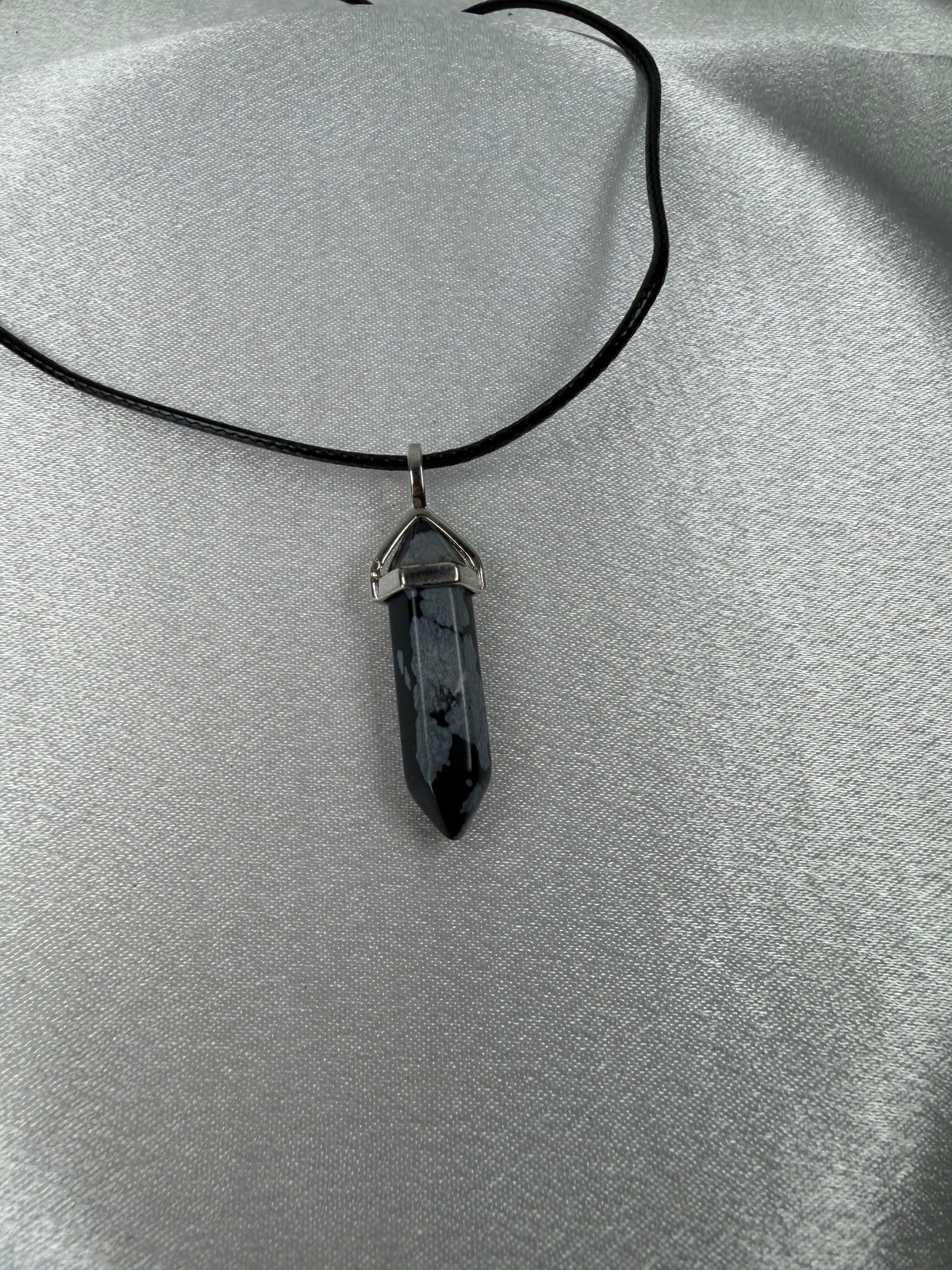 Snowflake obsidian necklace crystal point pendant photographed against a light background