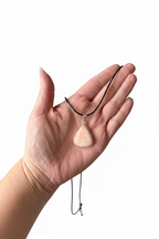 Treasured Energies scolecite teardrop pendant resting in an open palm