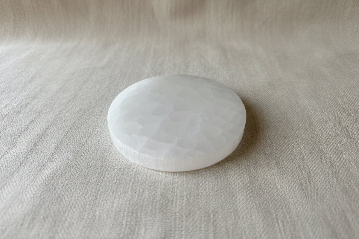 A round, faceted white stone or crystal ball resting on a textured beige fabric background.