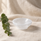 Small selenite bowl on warm linen with eucalyptus