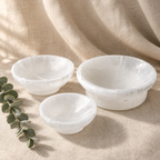 Three selenite bowls styled on warm linen with eucalyptus