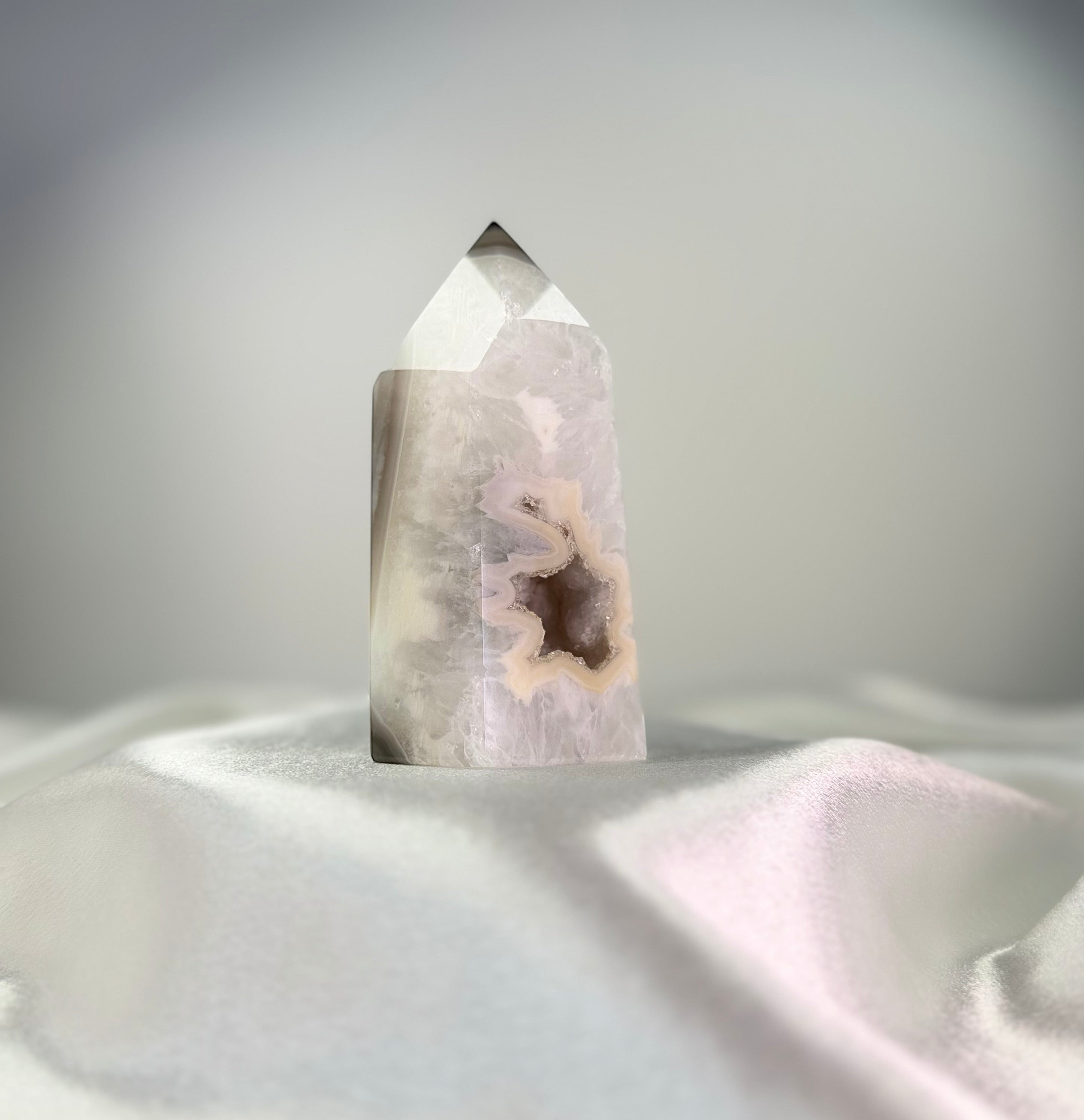 Treasured Energies polished agate point with white and black tones and a sparkling druzy crystal center on white silk.