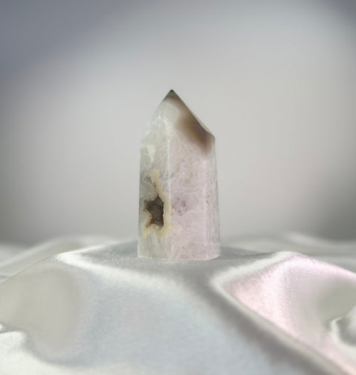 Treasured Energies polished agate crystal point with white and black tones and a sparkling druzy center on satin fabric