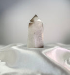 Treasured Energies polished agate crystal point with white and black tones and a sparkling druzy surface on white silk.
