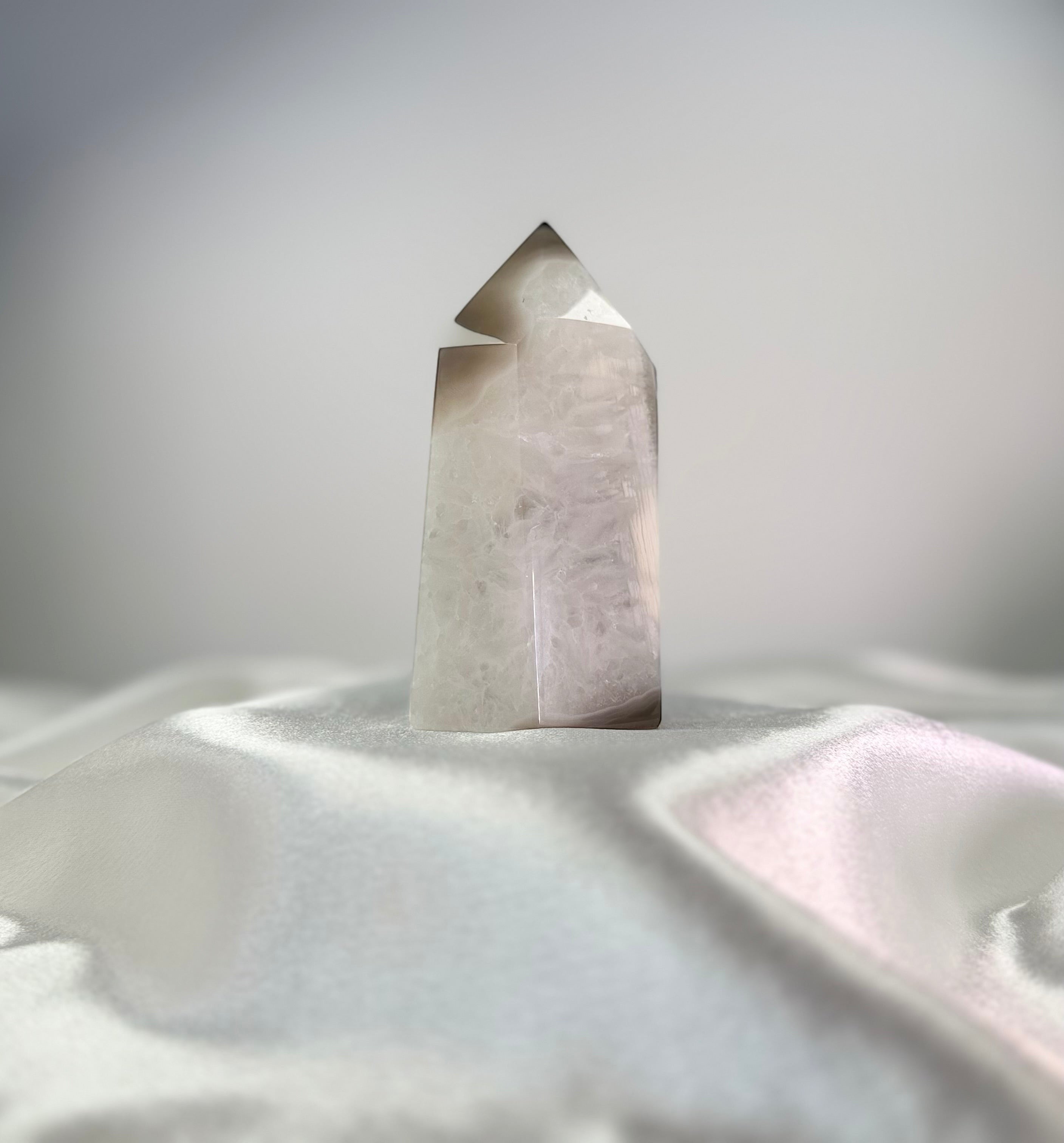 Treasured Energies polished agate crystal point with white and black tones and a sparkling druzy surface on white silk.