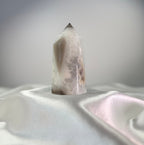 Treasured Energies white and black agate crystal point with sparkling druzy texture on a white satin fabric background.