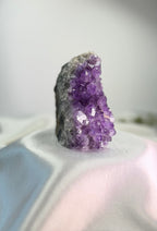 Treasured Energies freestanding amethyst crystal cluster with deep purple points on a white satin fabric background