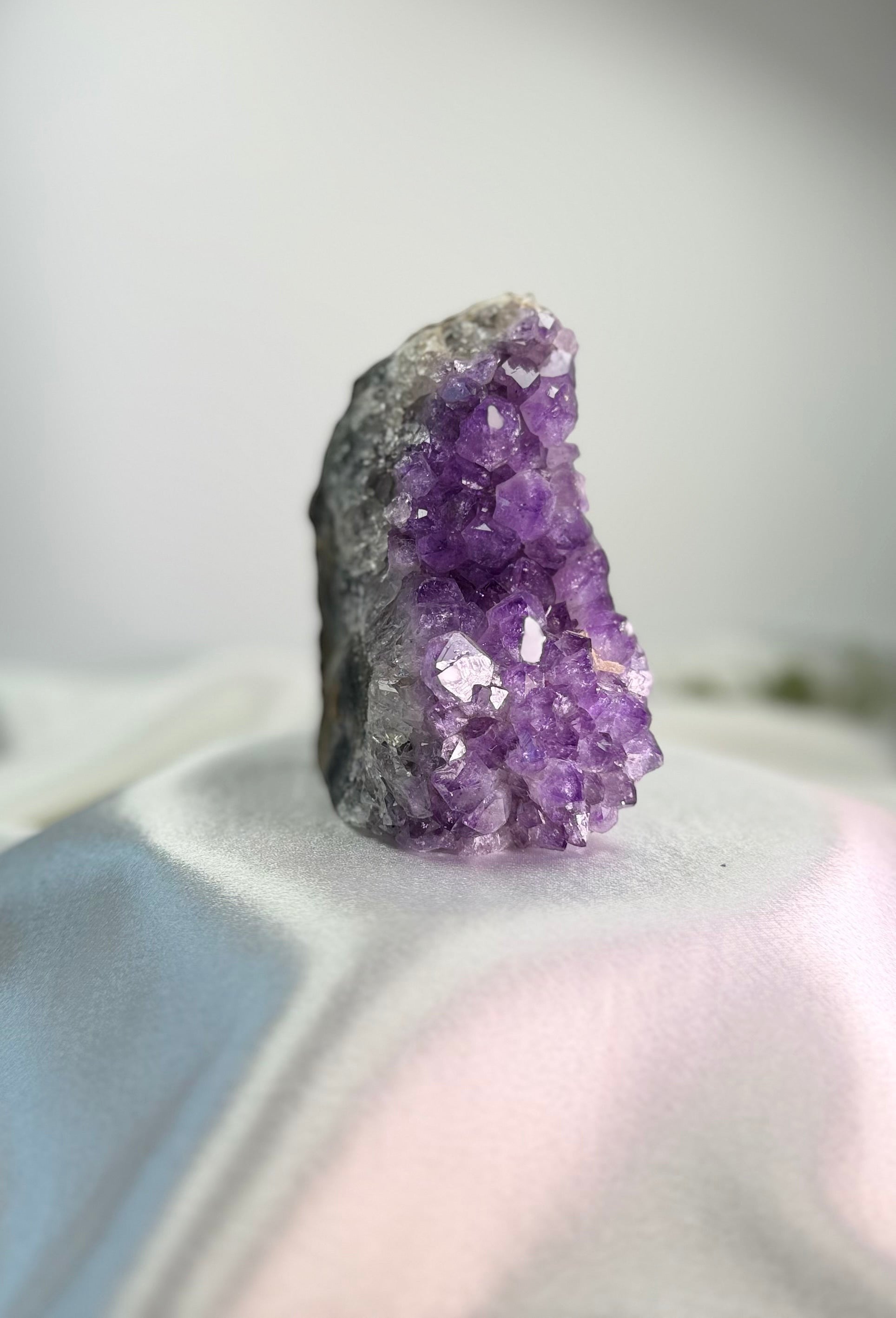 Treasured Energies freestanding amethyst crystal cluster with deep purple points on a white satin fabric background