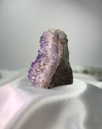 Treasured Energies freestanding amethyst cluster with deep purple crystals on a white satin background