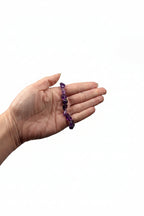 Treasured Energies amethyst bracelet crystal chip bracelet held in a hand against a soft white fabric background.