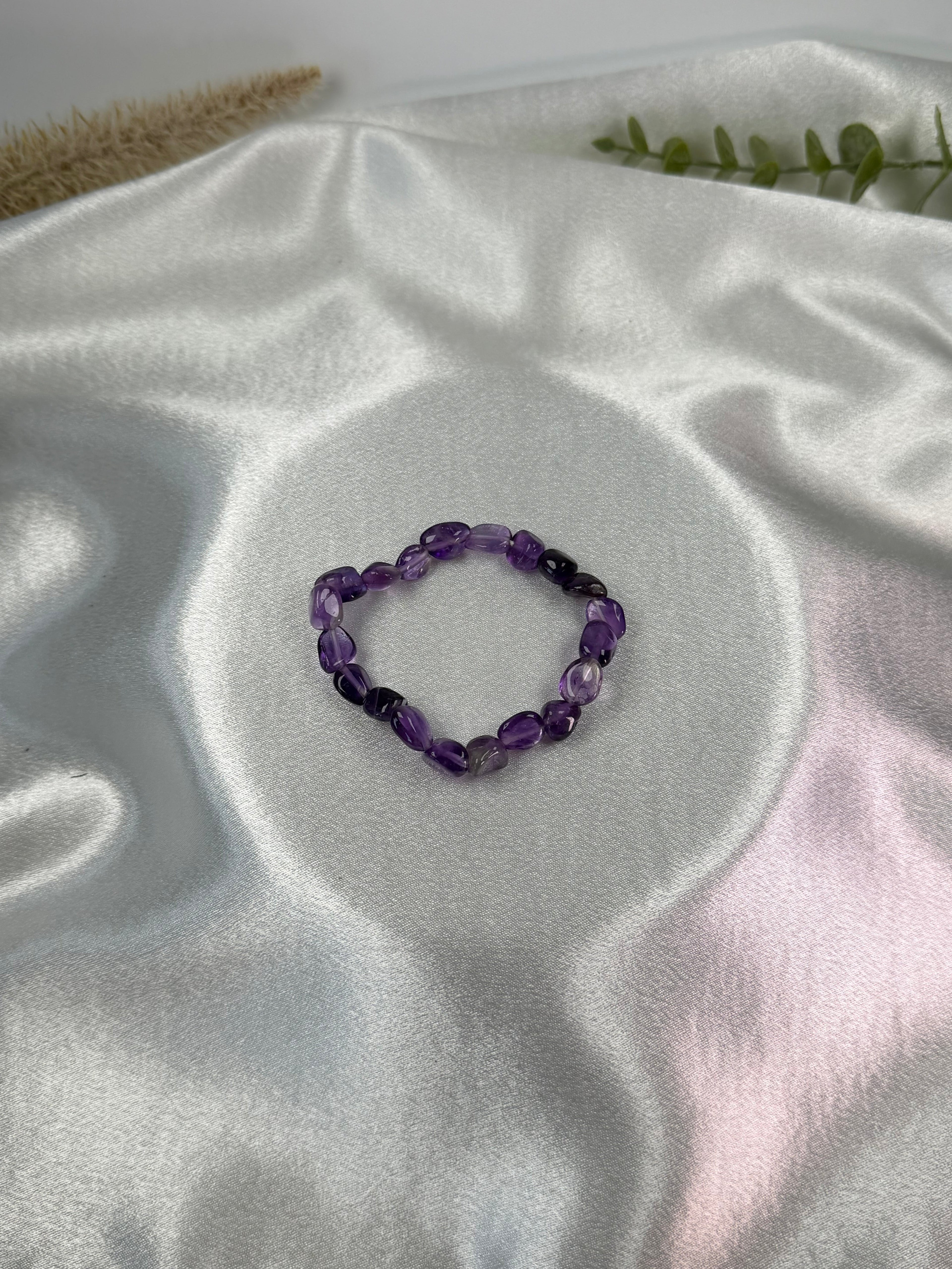 Treasured Energies amethyst crystal chip bracelet on a white satin background for healing and spiritual balance.