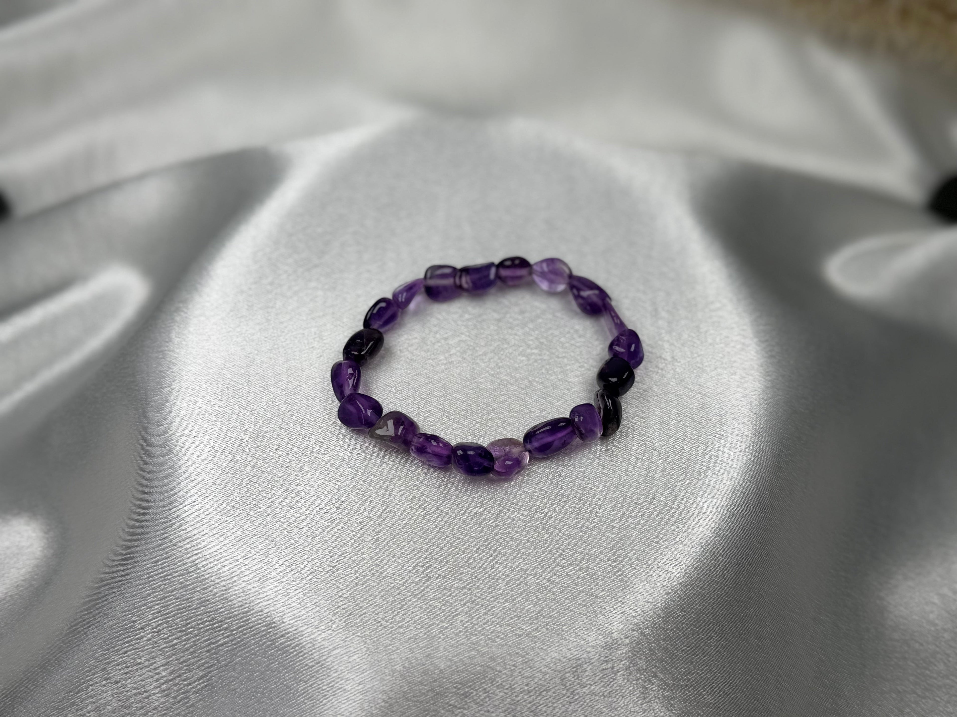 Treasured Energies amethyst crystal chip bracelet on a smooth silver satin background