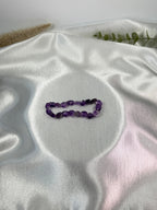 Treasured Energies amethyst bracelet crystal chip bracelet on a soft white satin fabric background