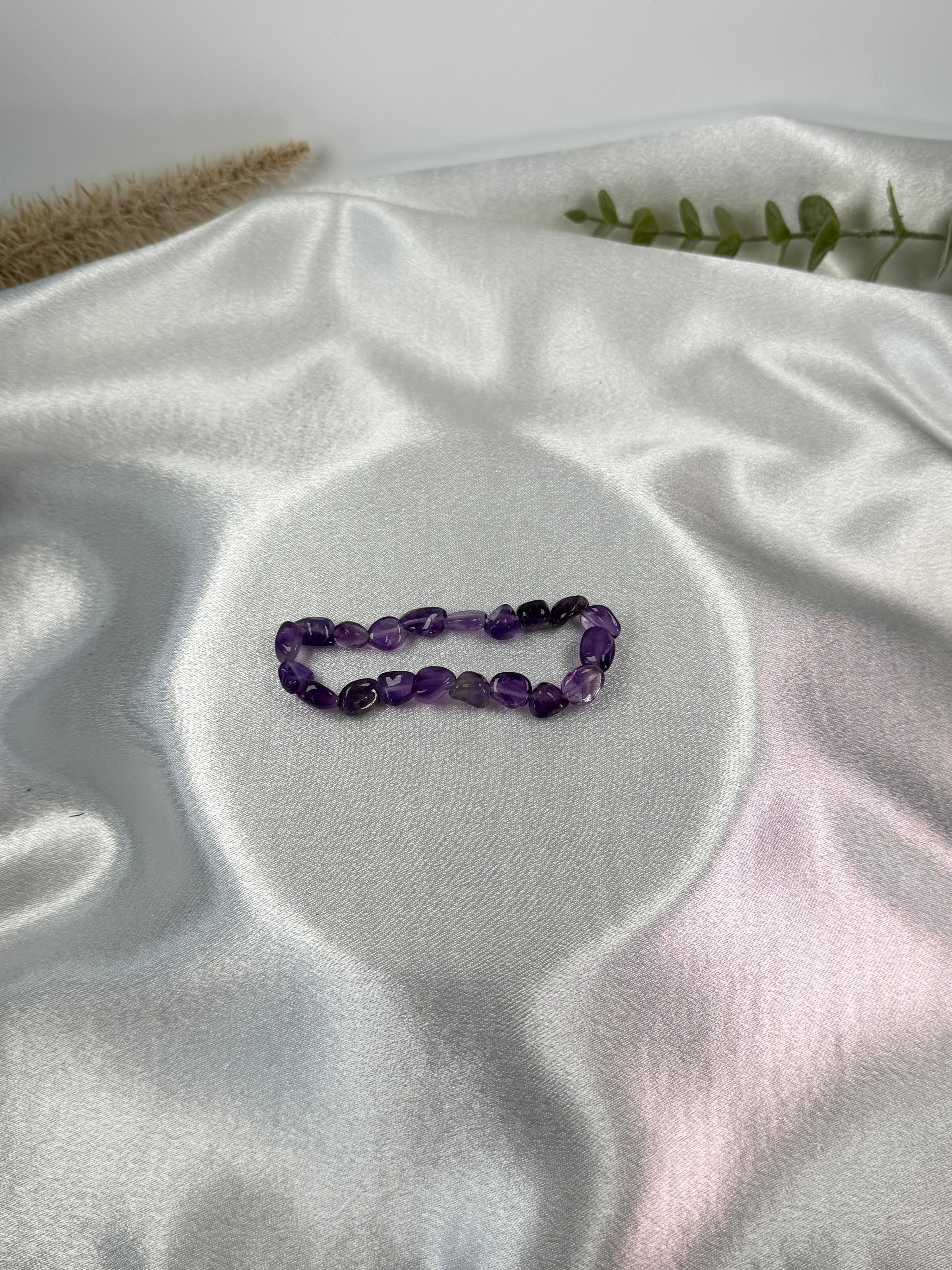 Treasured Energies amethyst crystal chip bracelet on a soft white satin fabric background