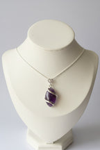 Treasured Energies amethyst crystal pendant necklace with a silver spiral wrap on a white display bust