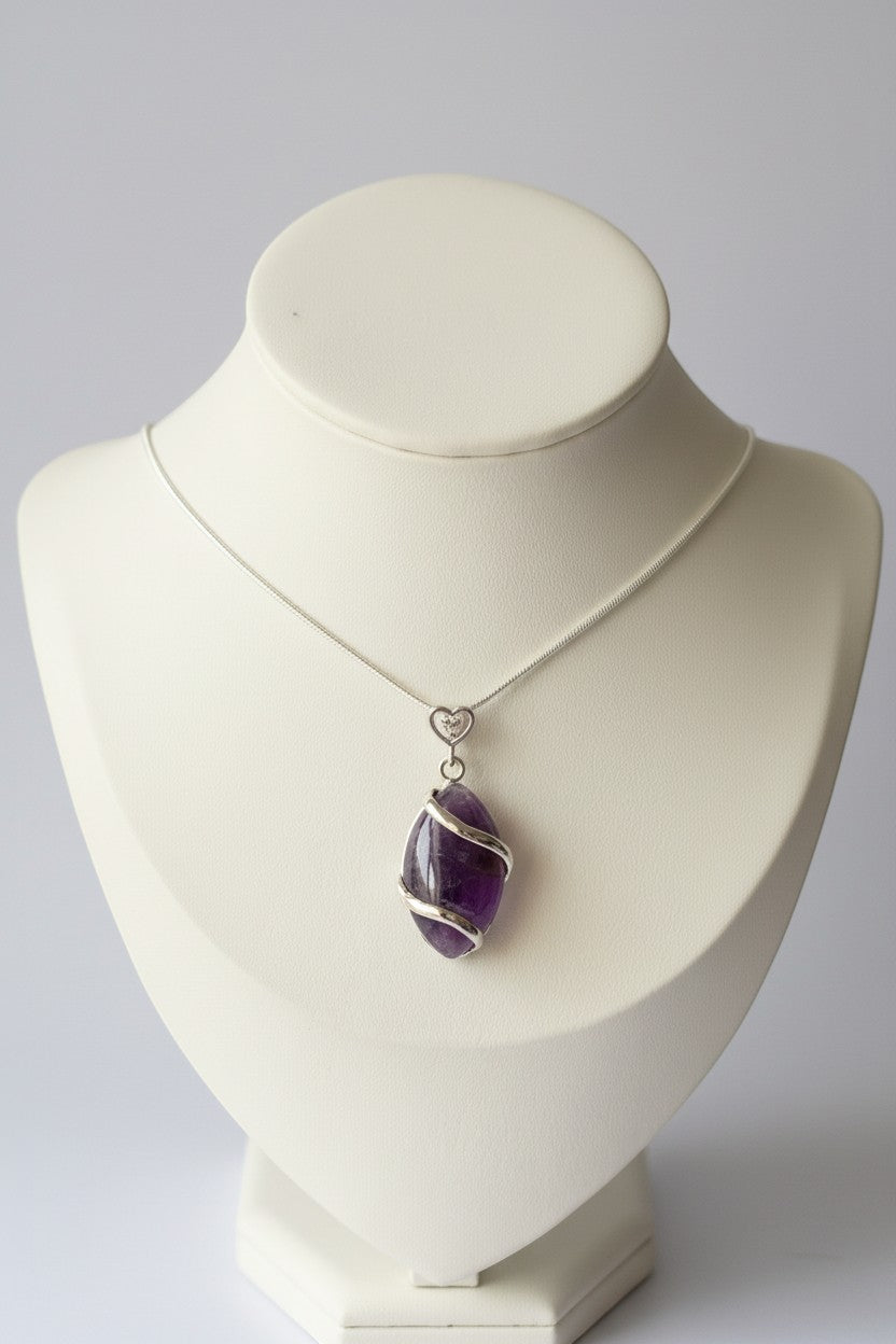 Treasured Energies amethyst crystal pendant necklace with a silver spiral wrap on a white display bust