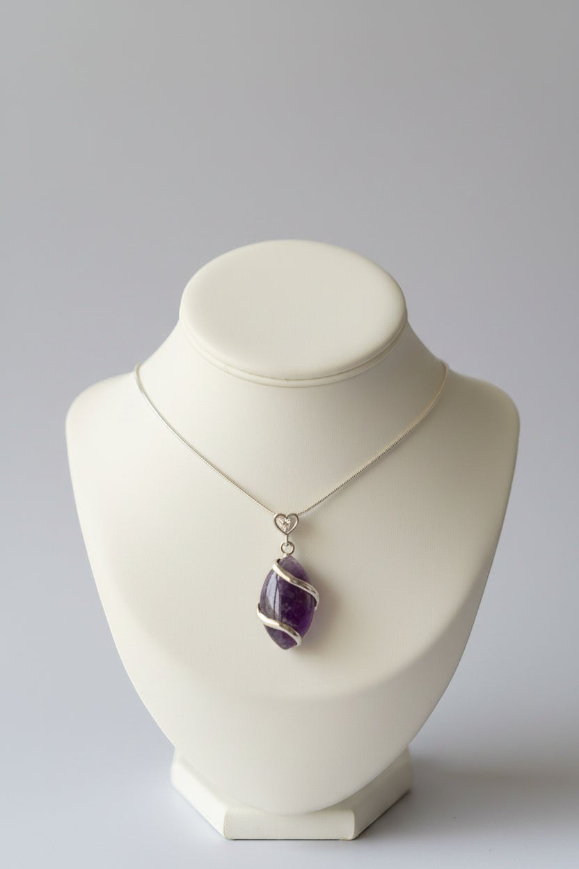 Treasured Energies amethyst natural crystal pendant necklace with a silver wire wrap on a display bust.