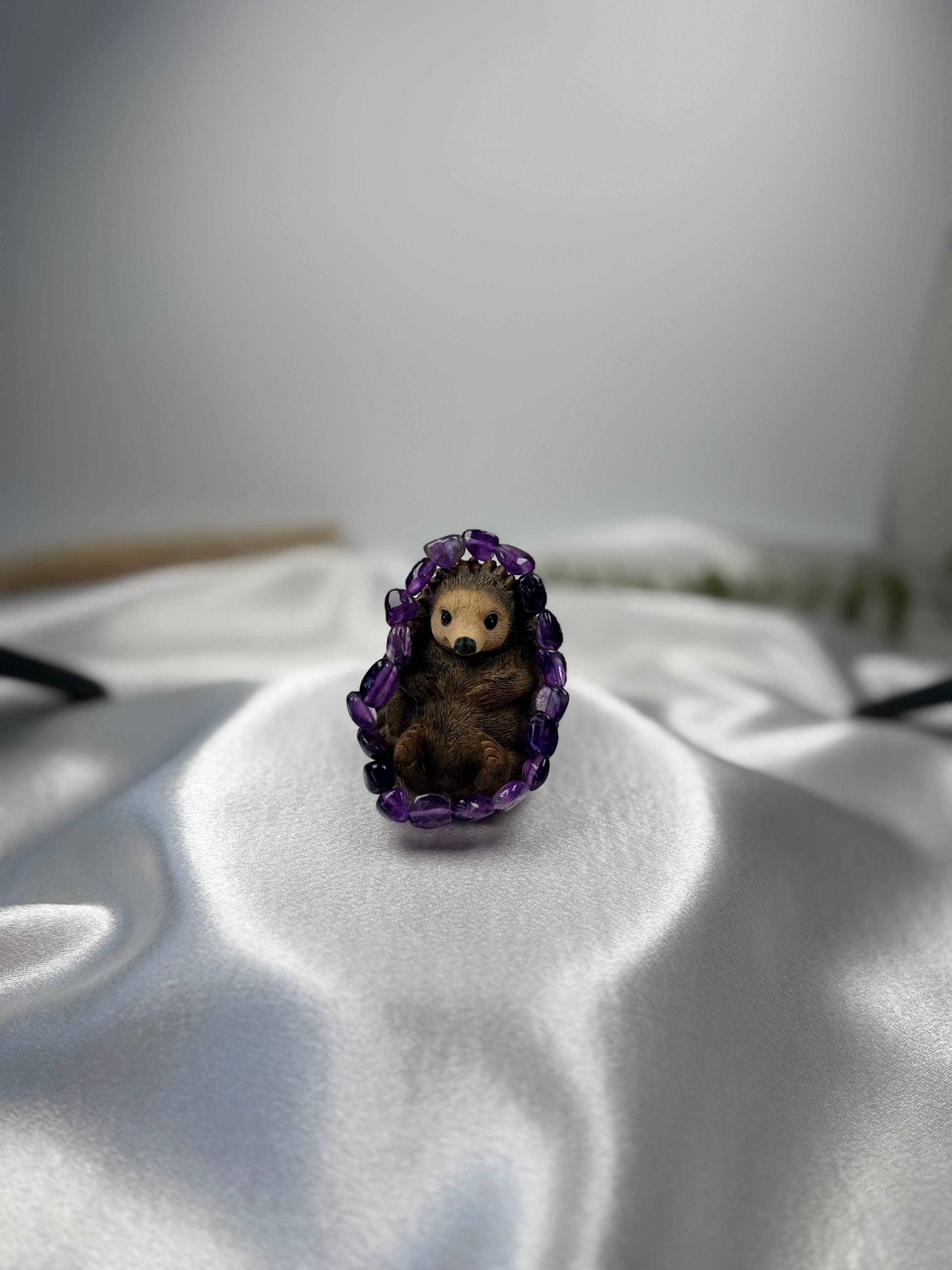Treasured Energies amethyst crystal bracelet featuring a small, cute hedgehog figurine nestled inside the purple stones.