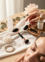 Treasured Energies black obsidian facial massage rollers with rose gold accents on a table with skincare products.