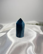 Treasured Energies blue agate crystal tower with a polished point on a white satin background