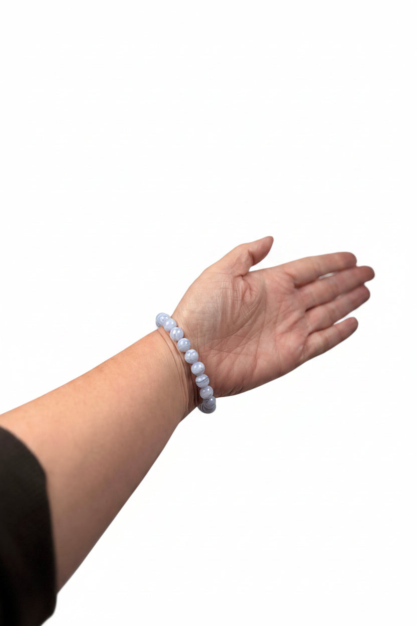 Treasured Energies blue lace agate crystal bead bracelet worn on a wrist against a soft white satin background