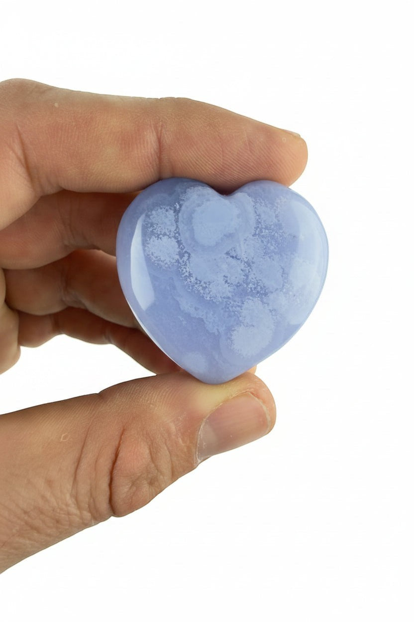 Treasured Energies polished blue lace agate crystal heart held in a hand, showing soft blue and white banded patterns.