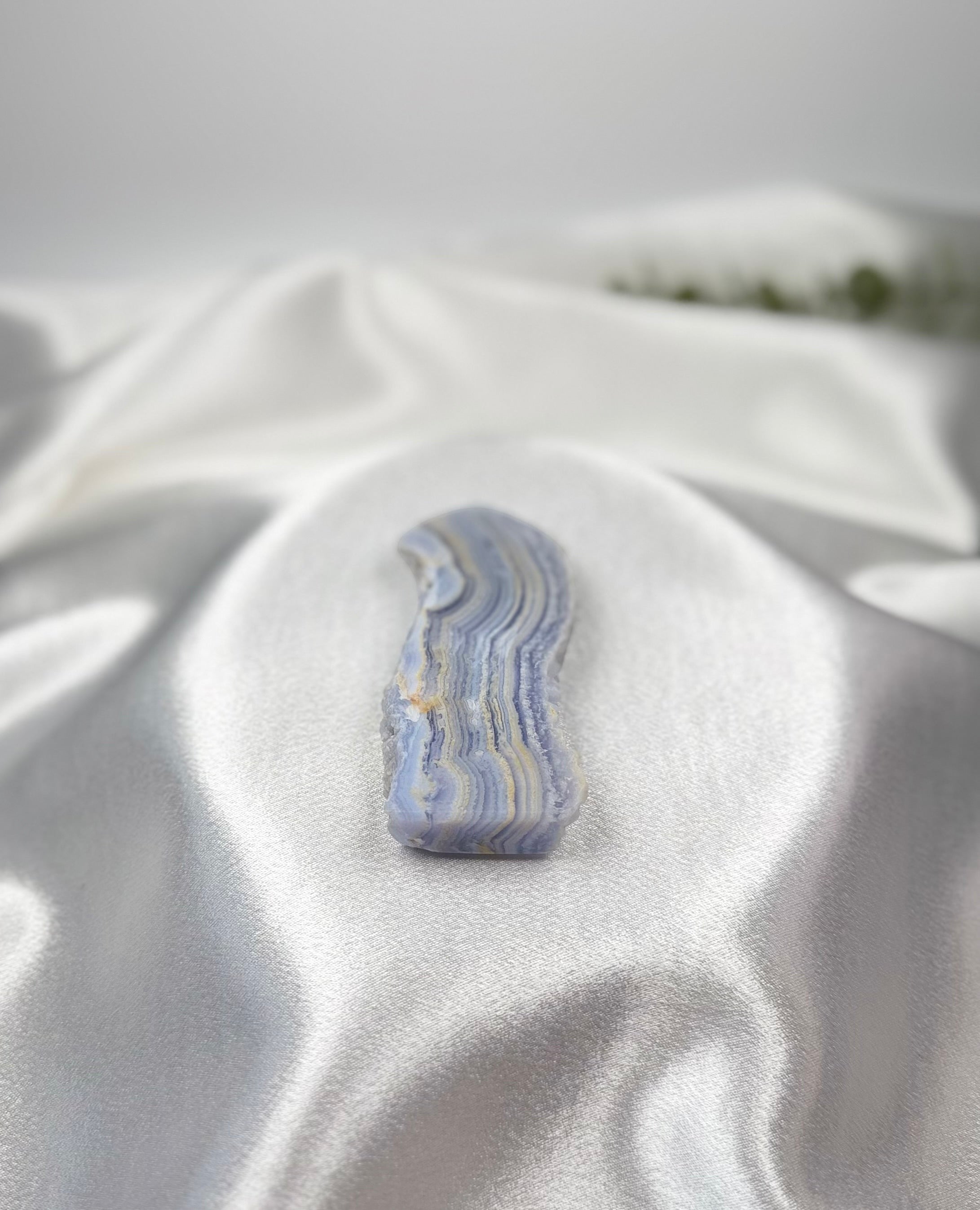 Treasured Energies Blue Lace Agate tower point featuring delicate blue and white banded layers on white silk fabric.