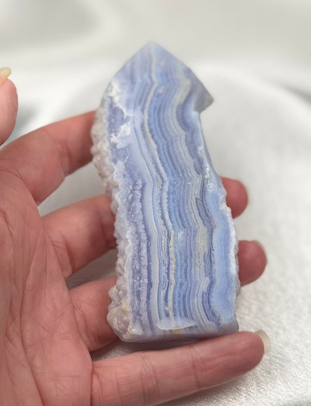 Treasured Energies Blue Lace Agate tower point with delicate blue and white banded layers held in a hand.