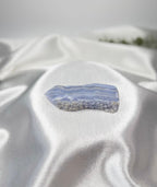Treasured Energies Blue Lace Agate tower point with delicate blue and white banding on a soft white satin background.