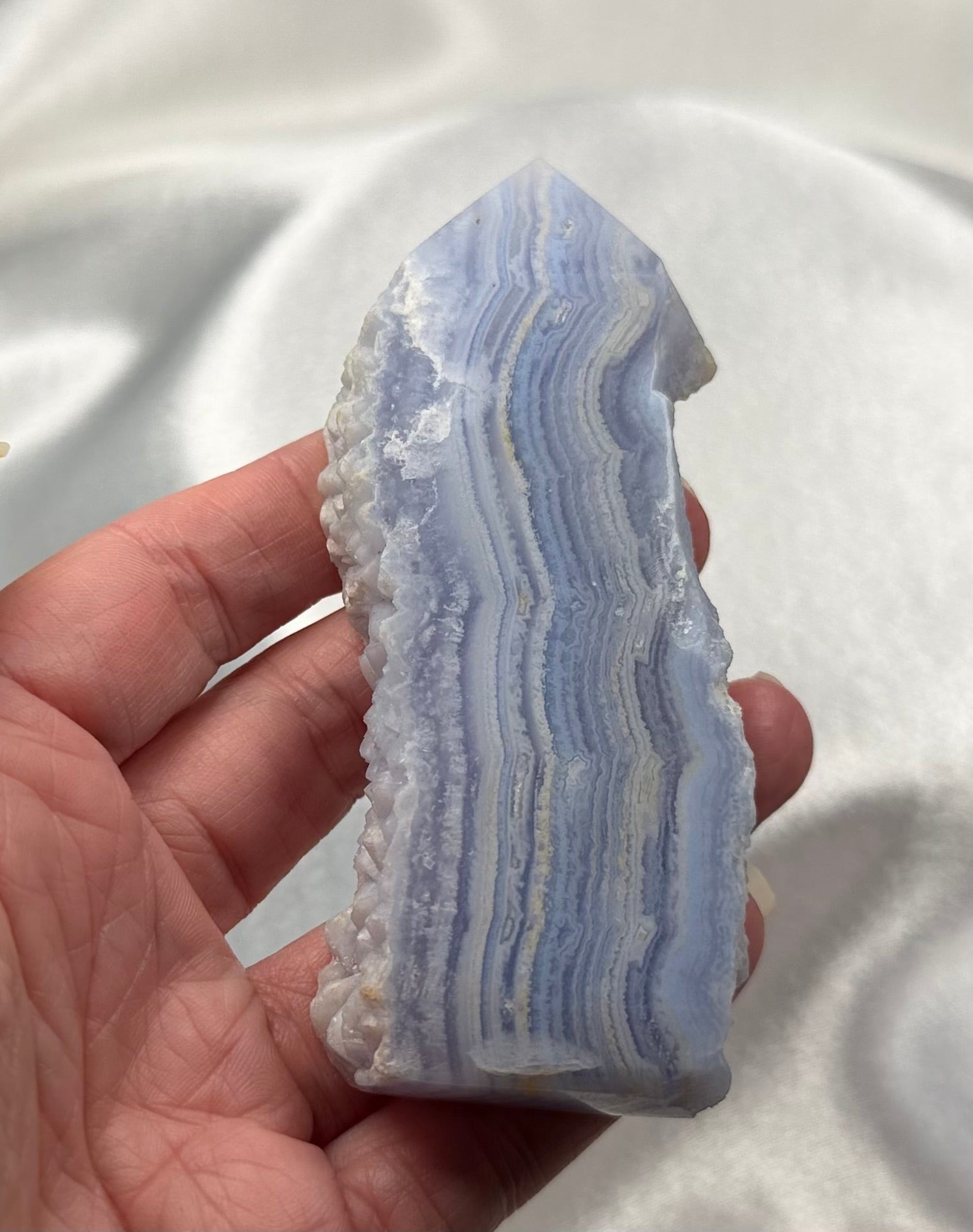 Treasured Energies Blue Lace Agate tower point with delicate blue and white banded layers held in a hand.