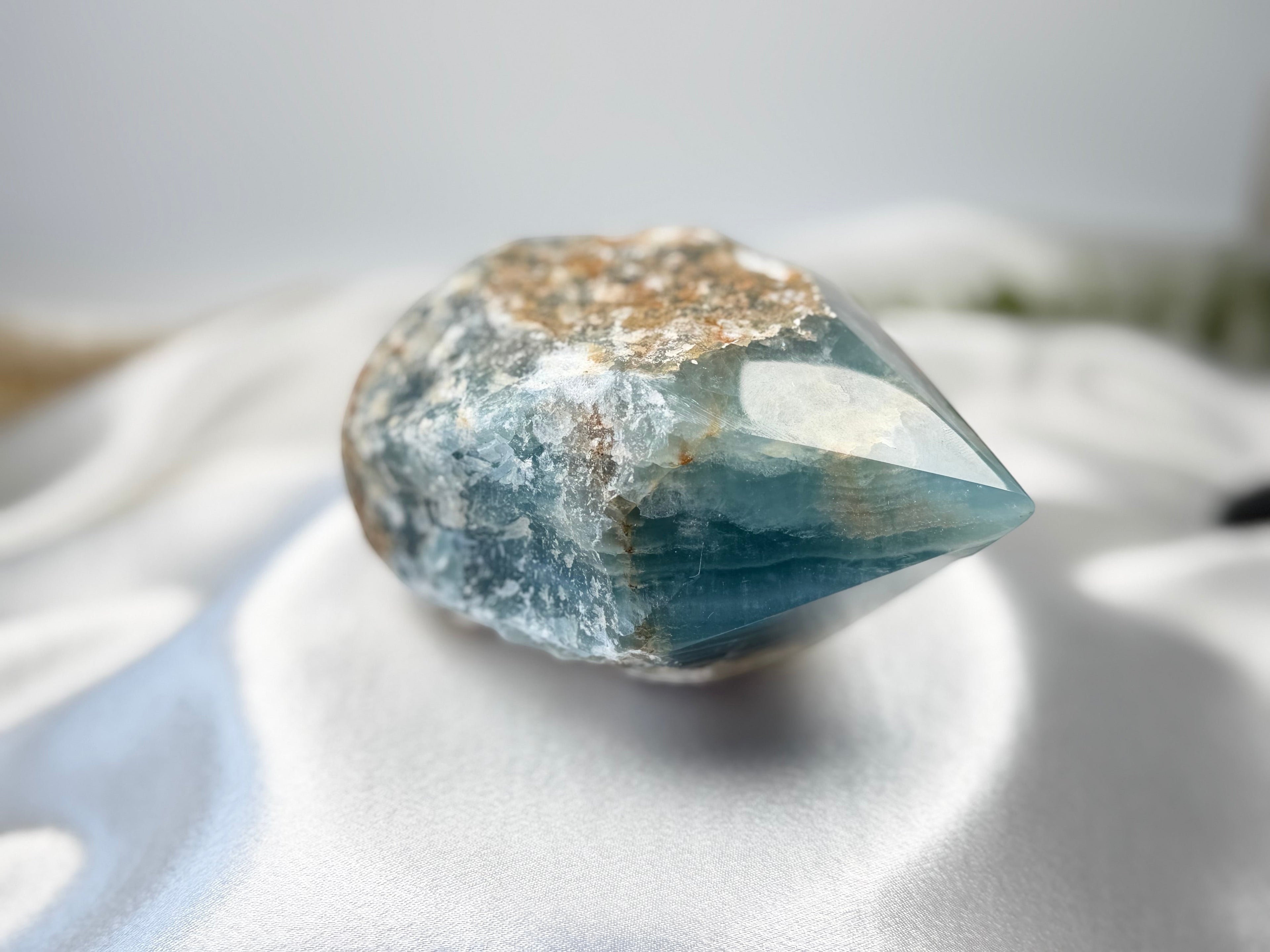 Treasured Energies Blue Onyx crystal with a raw, textured base and a smooth, polished faceted tower point.