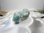 Treasured Energies blue onyx crystal tower with a raw, unpolished base and a smooth, polished point on white silk.
