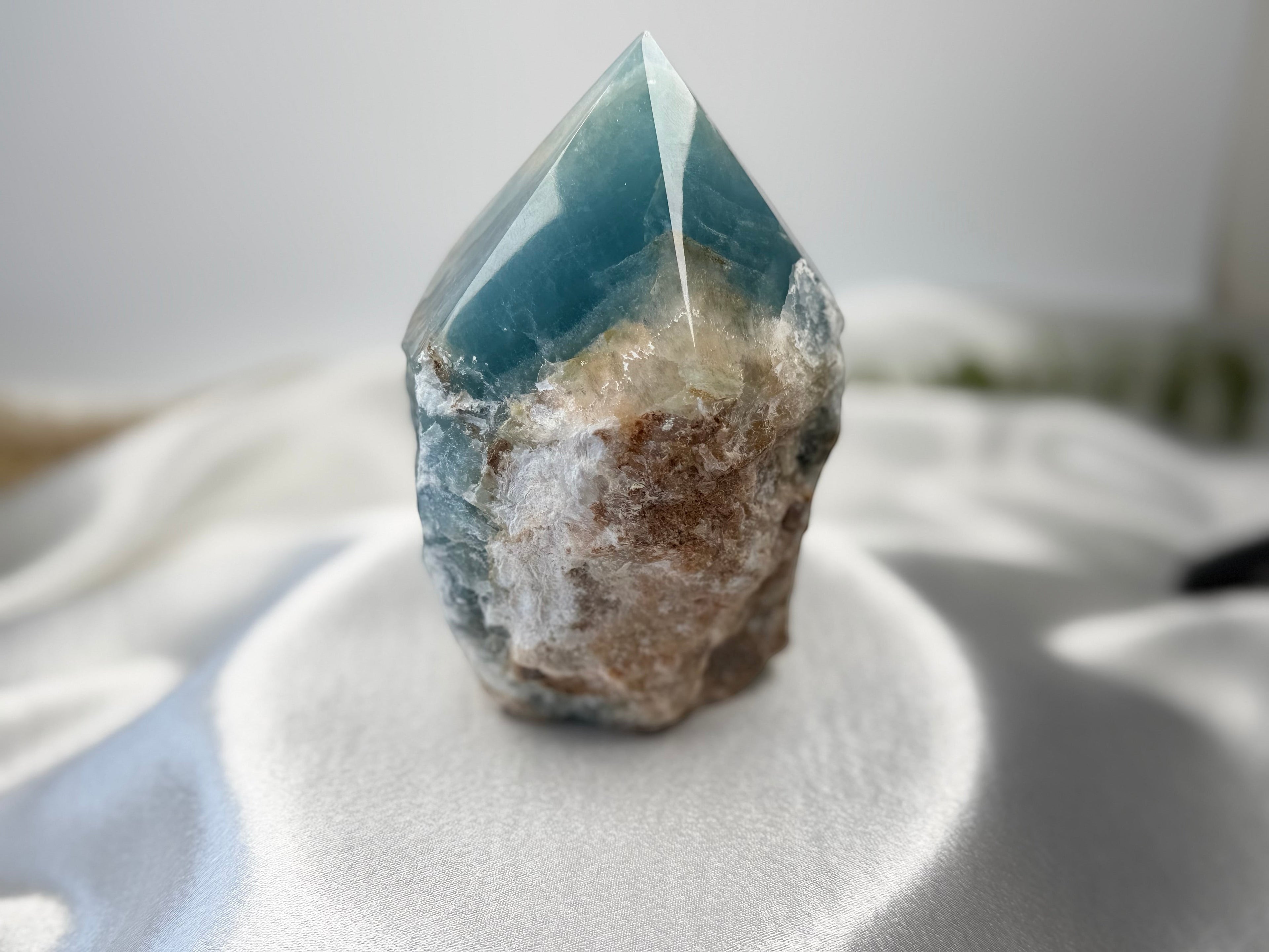 Treasured Energies Blue Onyx crystal tower with a raw, textured base and a smooth, polished pointed top.