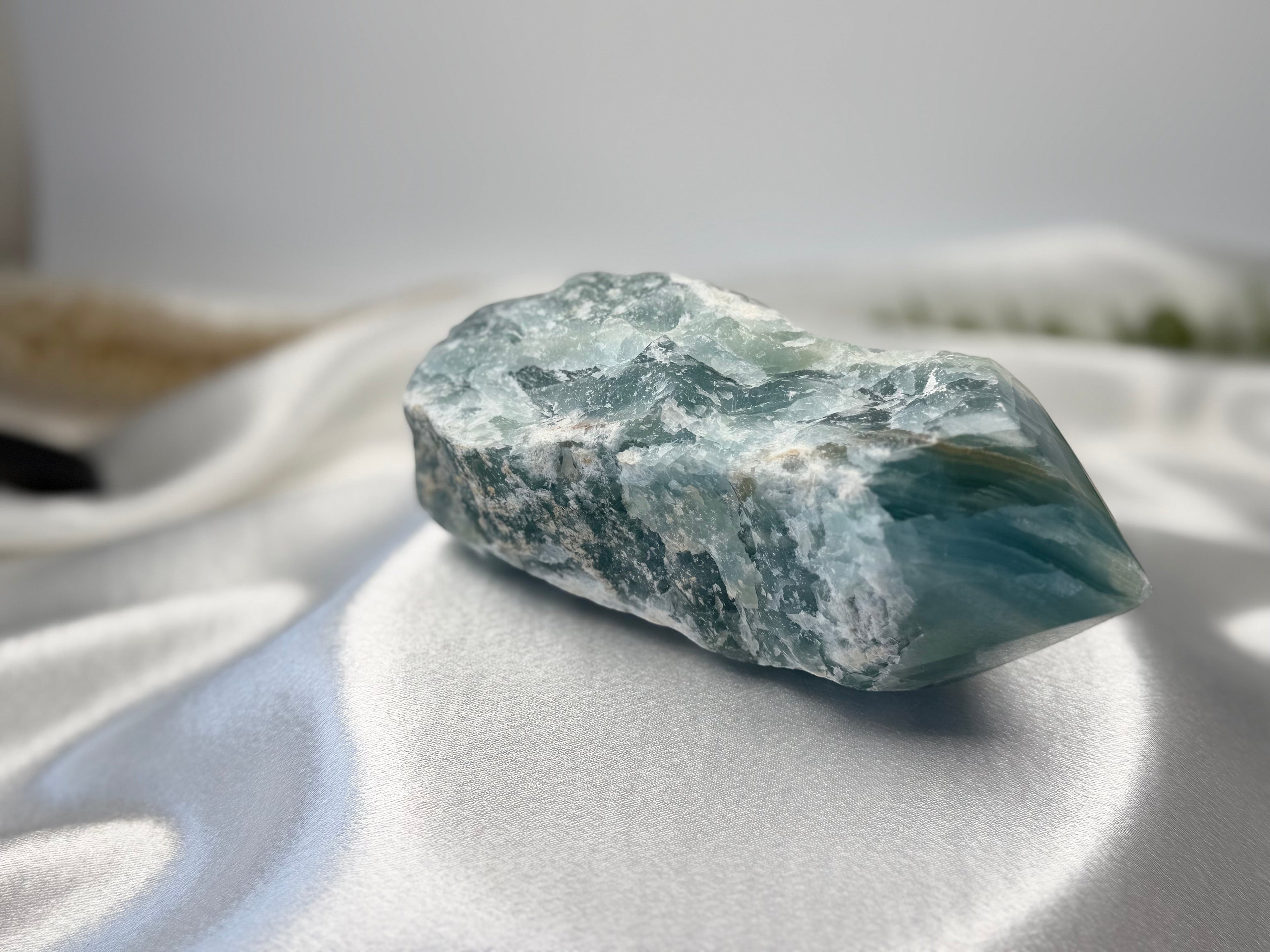 Treasured Energies blue onyx crystal tower with a raw, unpolished base and a smooth, faceted polished point on silk.