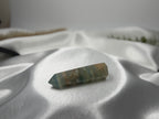 Treasured Energies polished Blue Onyx crystal tower point resting on soft white satin fabric