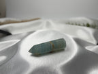 Treasured Energies polished blue onyx crystal tower with natural banding resting on a soft white satin fabric.
