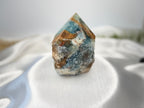 Treasured Energies blue onyx crystal tower with a raw, unpolished base and a smooth, faceted point on white silk.