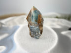 Treasured Energies blue onyx crystal tower with a raw, unpolished base and a smooth, faceted point on white silk.