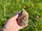 Treasured Energies Blue Onyx crystal tower with a raw, unpolished base and smooth, faceted point held in a hand.
