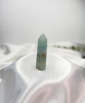 Treasured Energies polished blue onyx crystal tower with natural banding on a white satin fabric background.