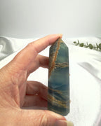 Treasured Energies blue onyx crystal tower held in hand, featuring natural brown banding and a polished finish.