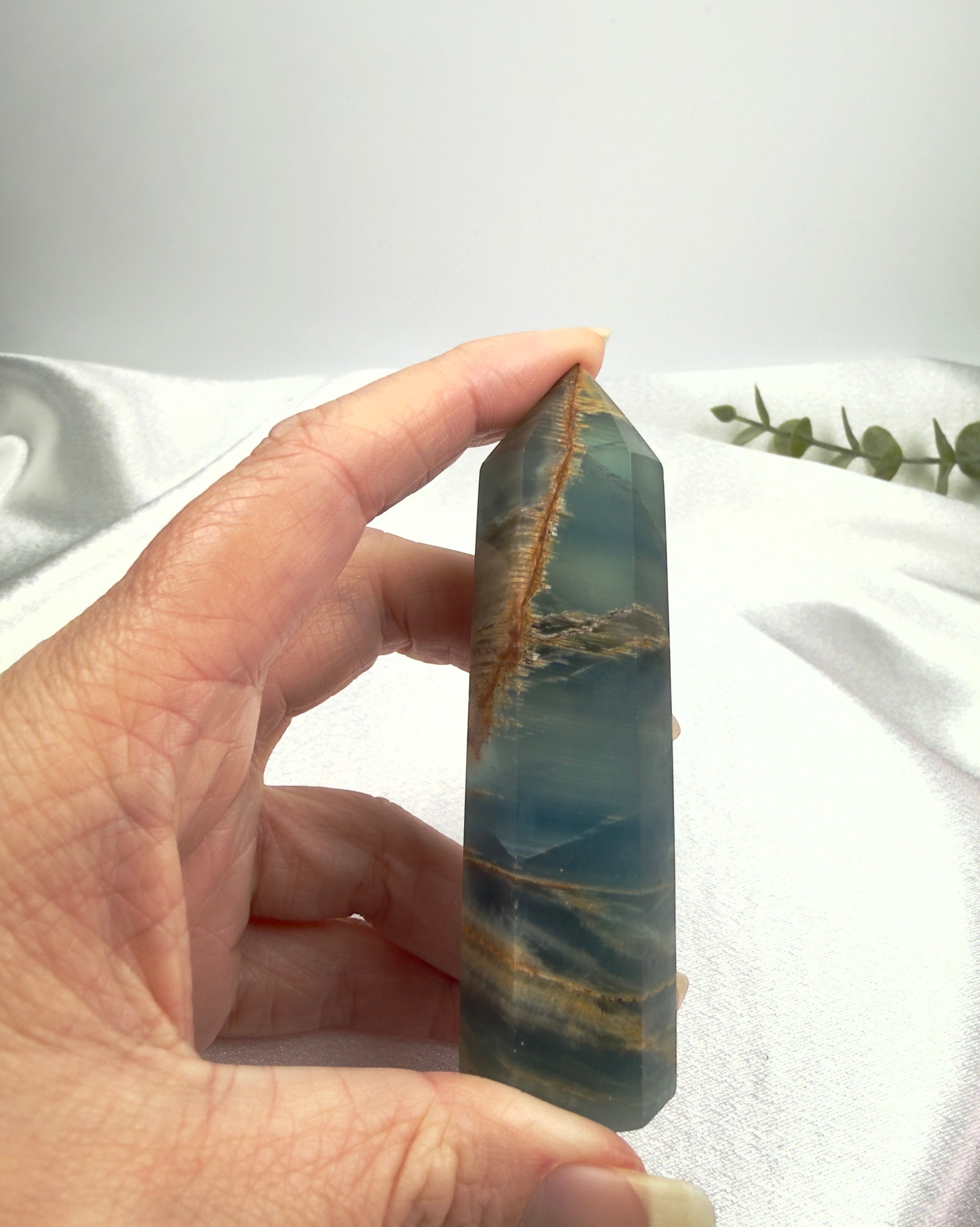 Treasured Energies blue onyx crystal tower held in hand, featuring natural brown banding and a polished finish.